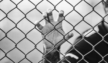 Hand grasping chain link fence