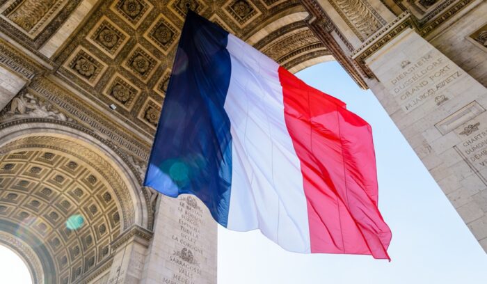 A large french flag fluttering under the Arc de Triomphe in Paris, for article on constitutional abortion rights