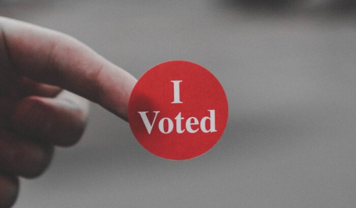 A person holding a sticker that says "I Voted"|loren joseph unsplash