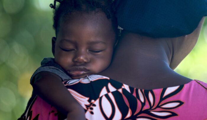 African girl sleeping on mother's shoulder, for article on global child mortality