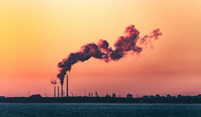 Smoky industrial emissions at sunset symbolizing need for CO2 to ethanol conversion technology