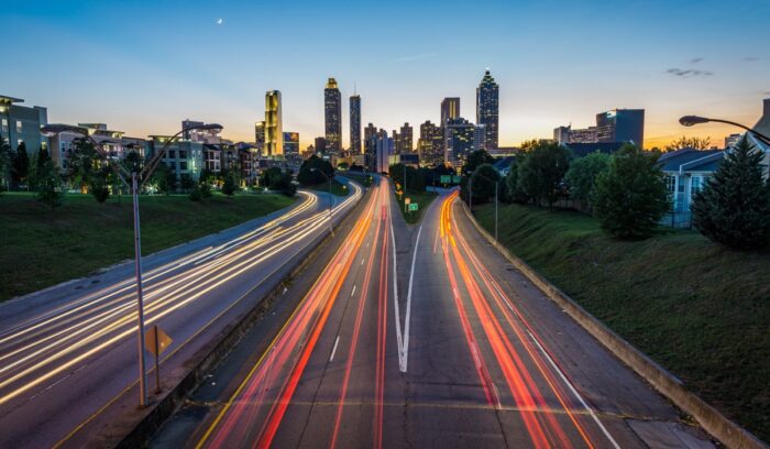 Blur of traffic lights in front of city skyline, for article on global EV sales