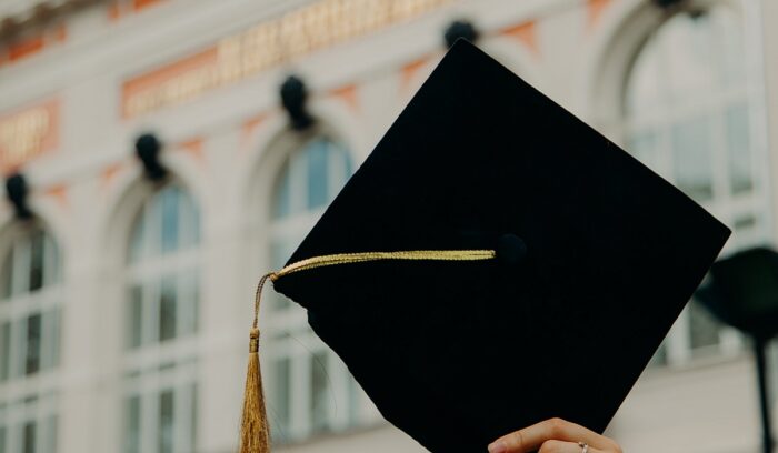 Commencement cap held in the air, for article on Yale Prison Education Initiative