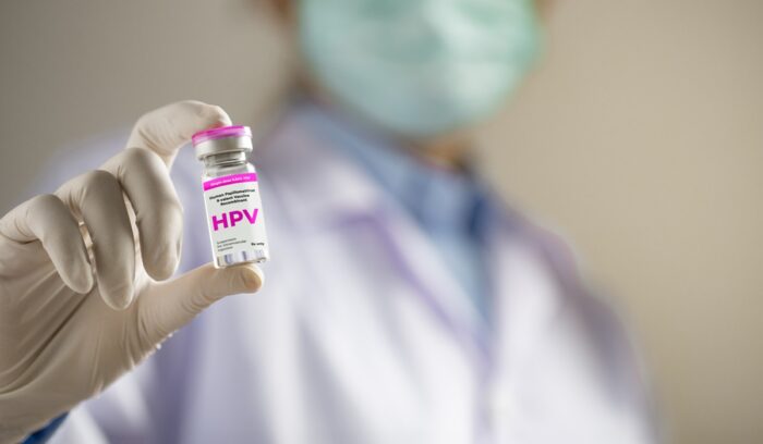 Doctor holding vial of HPV vaccine, for article on HPV vaccination