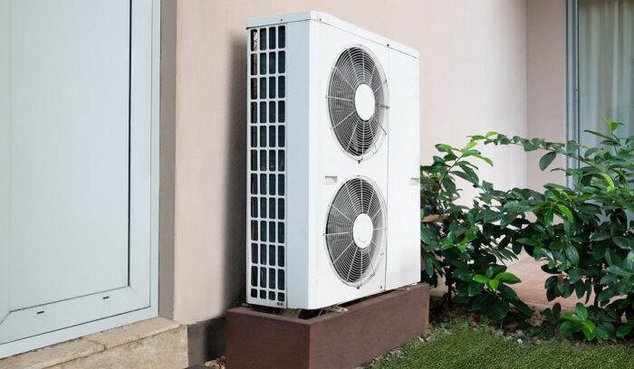 A modern heat pump unit mounted outside a residential home in winter for an article about heat pump adoption