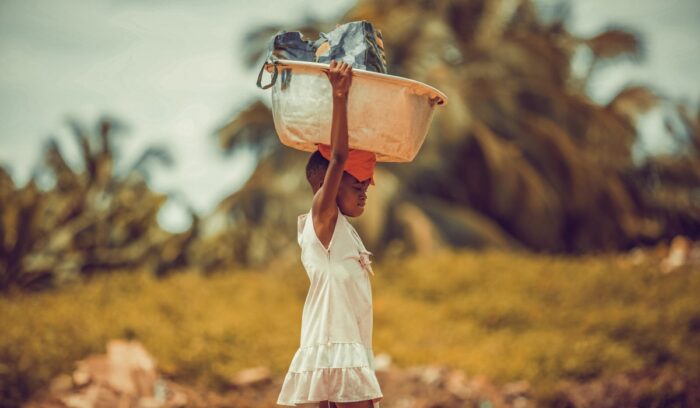 Ghanaian child carrying load on head, for article on R21 malaria vaccine