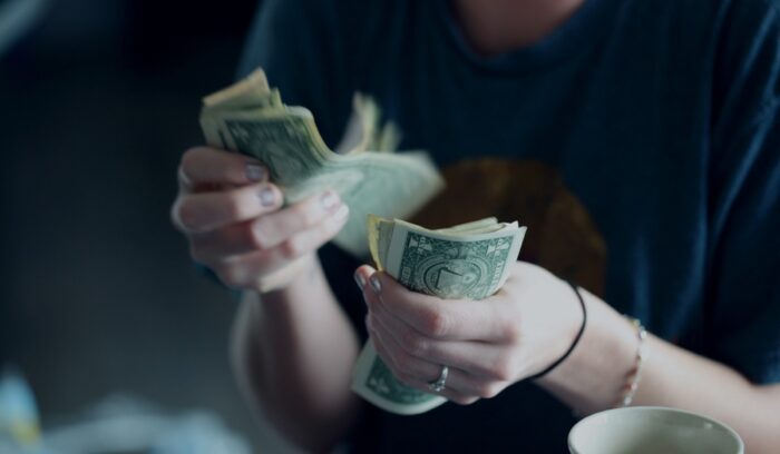Hands counting money symbolizing U.S. income inequality and the wealth gap between Americans