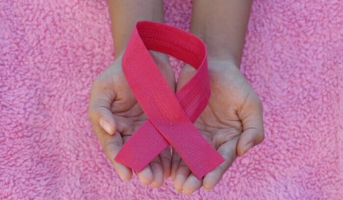 Holding breast cancer ribbon, for article on breast cancer recurrence blood test