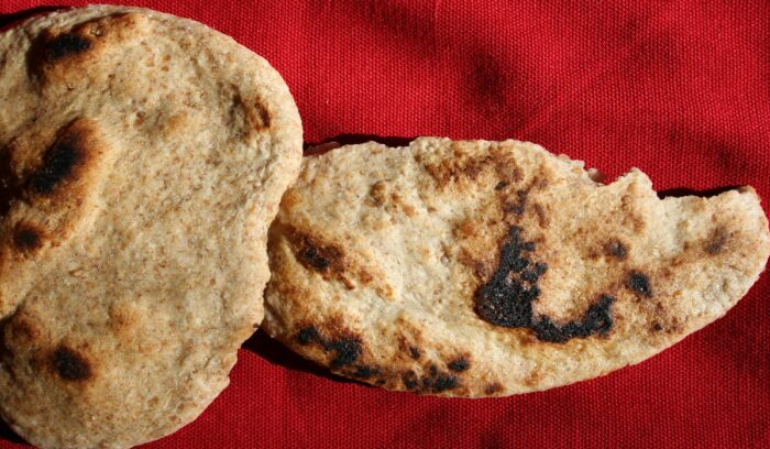 Home baked unleavened flour and water flatbread on a red tablecloth., for article on prehistoric flatbread
