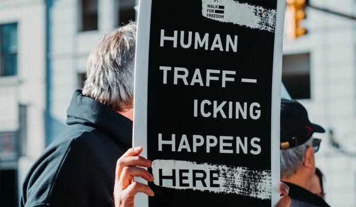 Man holding "Human trafficking happens here" sign|eunice stahl unsplash