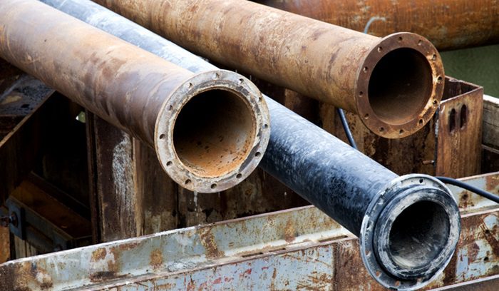 A worker replacing a corroded lead pipe in a residential street for an article about Flint lead pipe replacement
