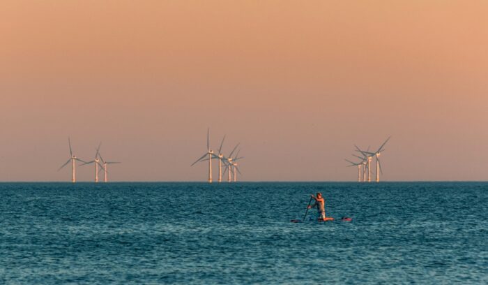 Offshore wind turbines with paddler in foreground, for article on offshore wind energy