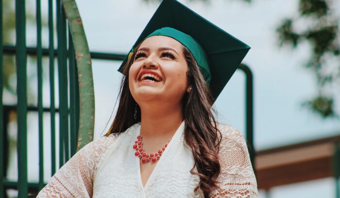 Woman in graduation garb smiling, for article on student loan forgiveness