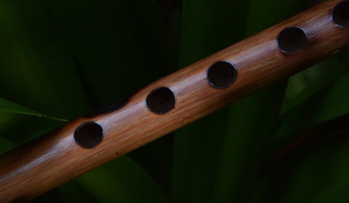 A carved bone flute resting on stone in a cave setting, for an article about Paleolithic flutes
