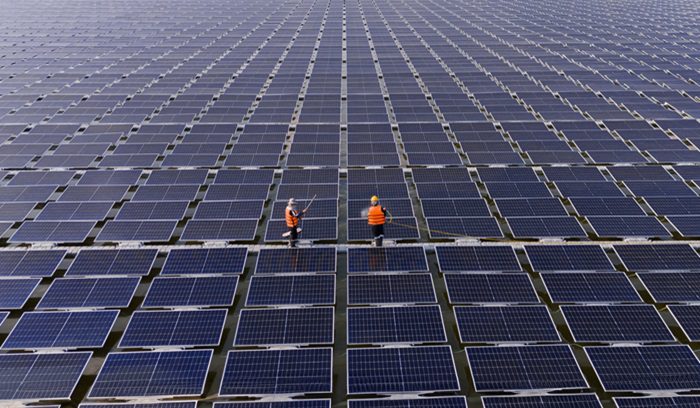 Professional workers clean and inspect solar panels on a floating buoy. Power plant with water, for article on China solar power