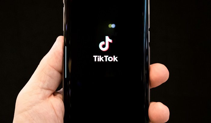 Someone holding a phone opening the TikTok app, for article on Brazil smartphone ban in schools