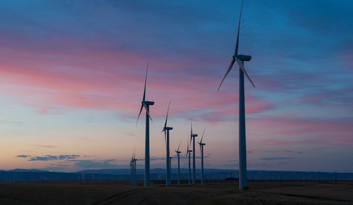 Solar panels and wind turbines generating power on open land for an article about U.S. clean electricity