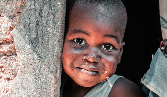 A young child eating a nutritious meal in a sunlit community setting for an article about child malnutrition eliminated