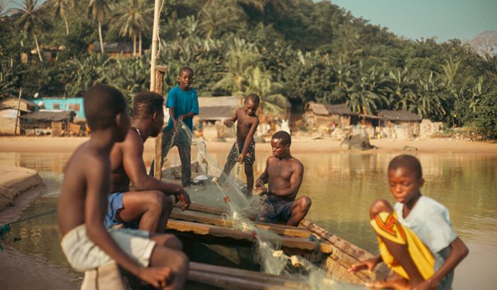 Ghanaian fishermen pulling nets from a wooden canoe for an article about Ghana's artisanal fishing zone
