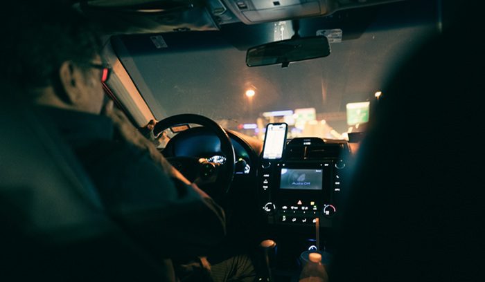 A ride-share driver in a car checking their phone, for an article about California gig worker rights and collective bargaining