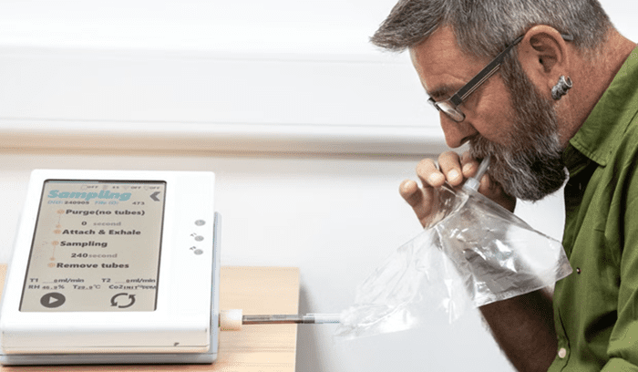 A patient breathing into a medical device for an article about pancreatic cancer breath test