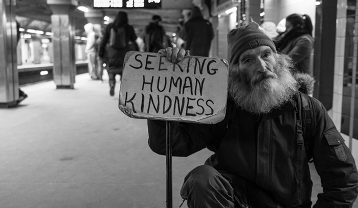 Person with "seeking human kindness" sign