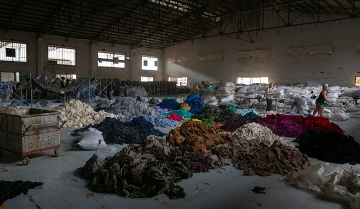 Piles of discarded clothing in a textile recycling facility for an article about the EU textile waste ban