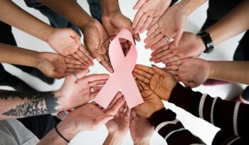 People holding breast cancer pin