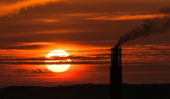 Sunset by smokestacks, for article on fossil fuel phaseout